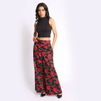Women’s luxury cotton satin flare pants in black with bold red rose print, styled with pointed heels