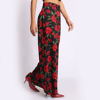 Women’s luxury cotton satin flare pants in black with bold red rose print, styled with pointed heels