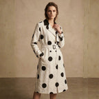 Woman wearing a white coat with black polka dots against a beige background