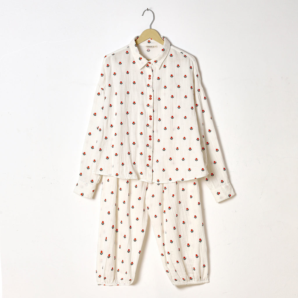 White pajama set with red polka dots on a hanger against a white background