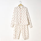 White pajama set with red polka dots on a hanger against a white background