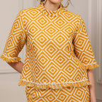 Person wearing a yellow and white patterned top with fringes on a neutral background