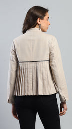 Woman wearing a beige blazer with a pleated design on a gray background