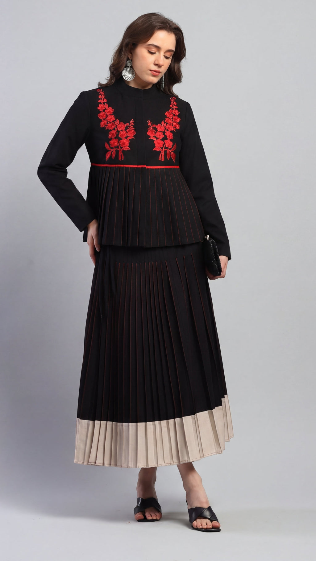 Woman wearing a black dress with red floral embroidery on a gray background