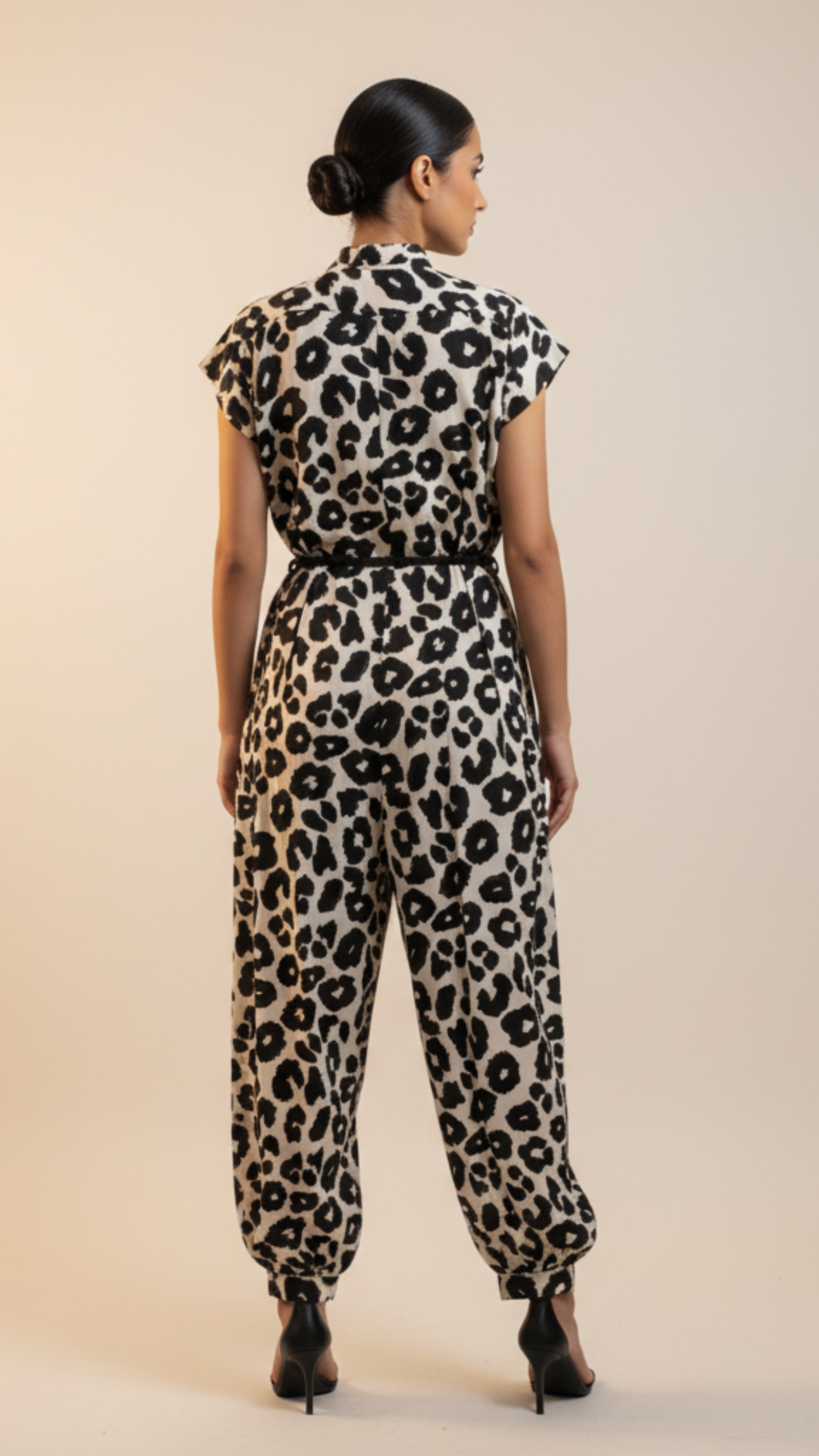 Woman wearing a leopard print jumpsuit on a beige background