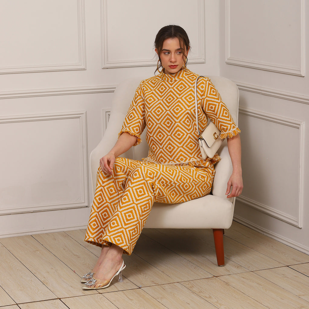 Woman in a yellow patterned outfit sitting on a white chair in a room with paneled walls.