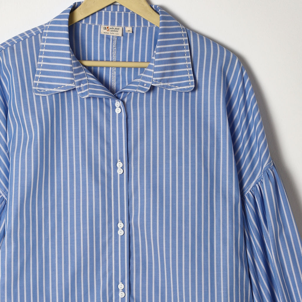 Blue and white striped shirt on a hanger against a white background