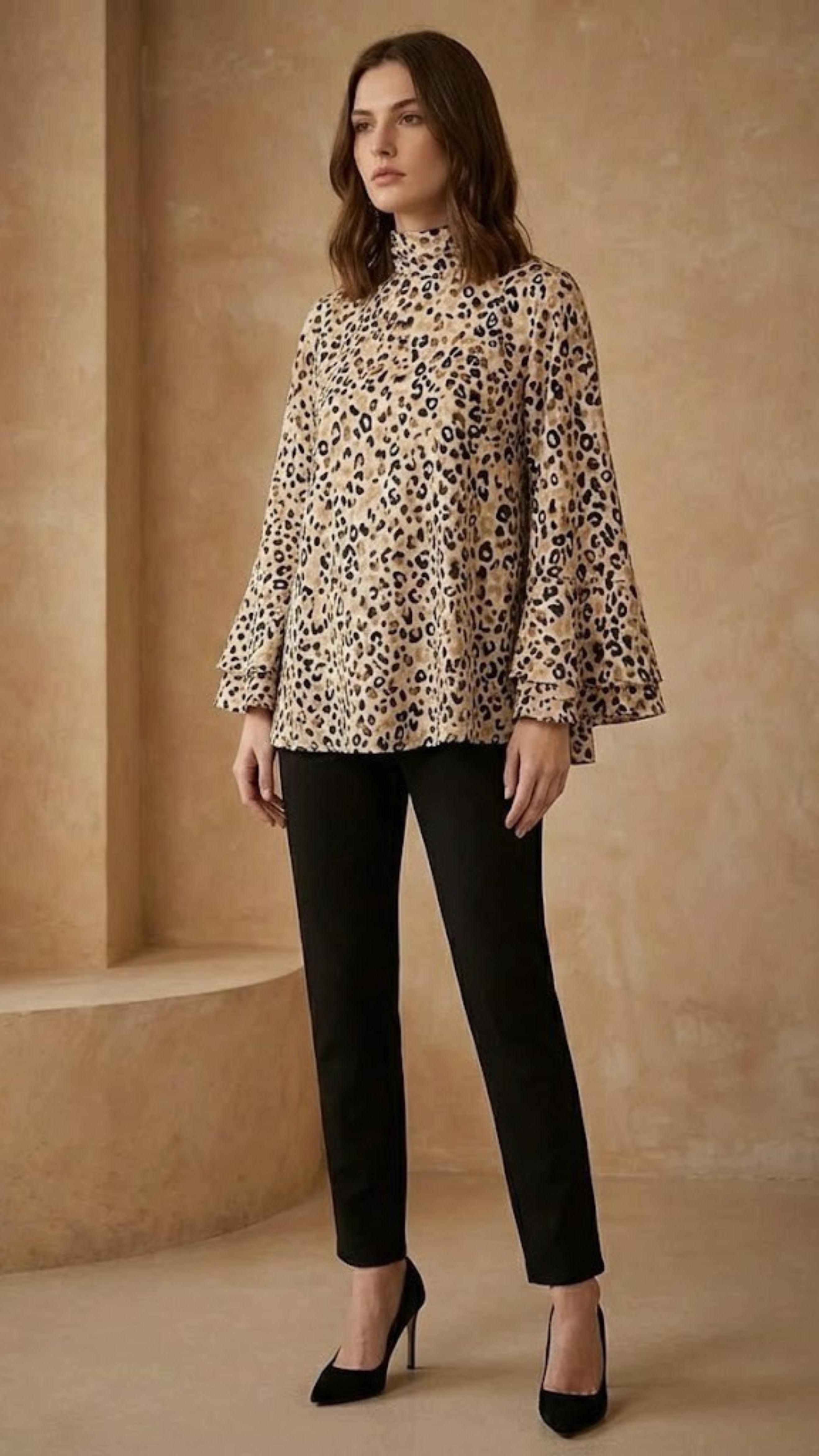 Woman wearing a leopard print blouse and black pants in a beige room.
