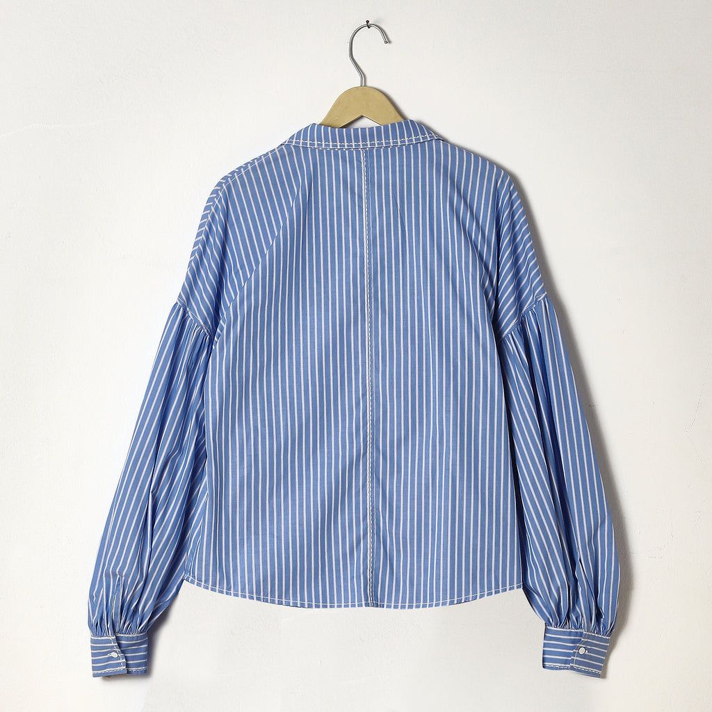 Blue and white striped shirt on a hanger against a white background