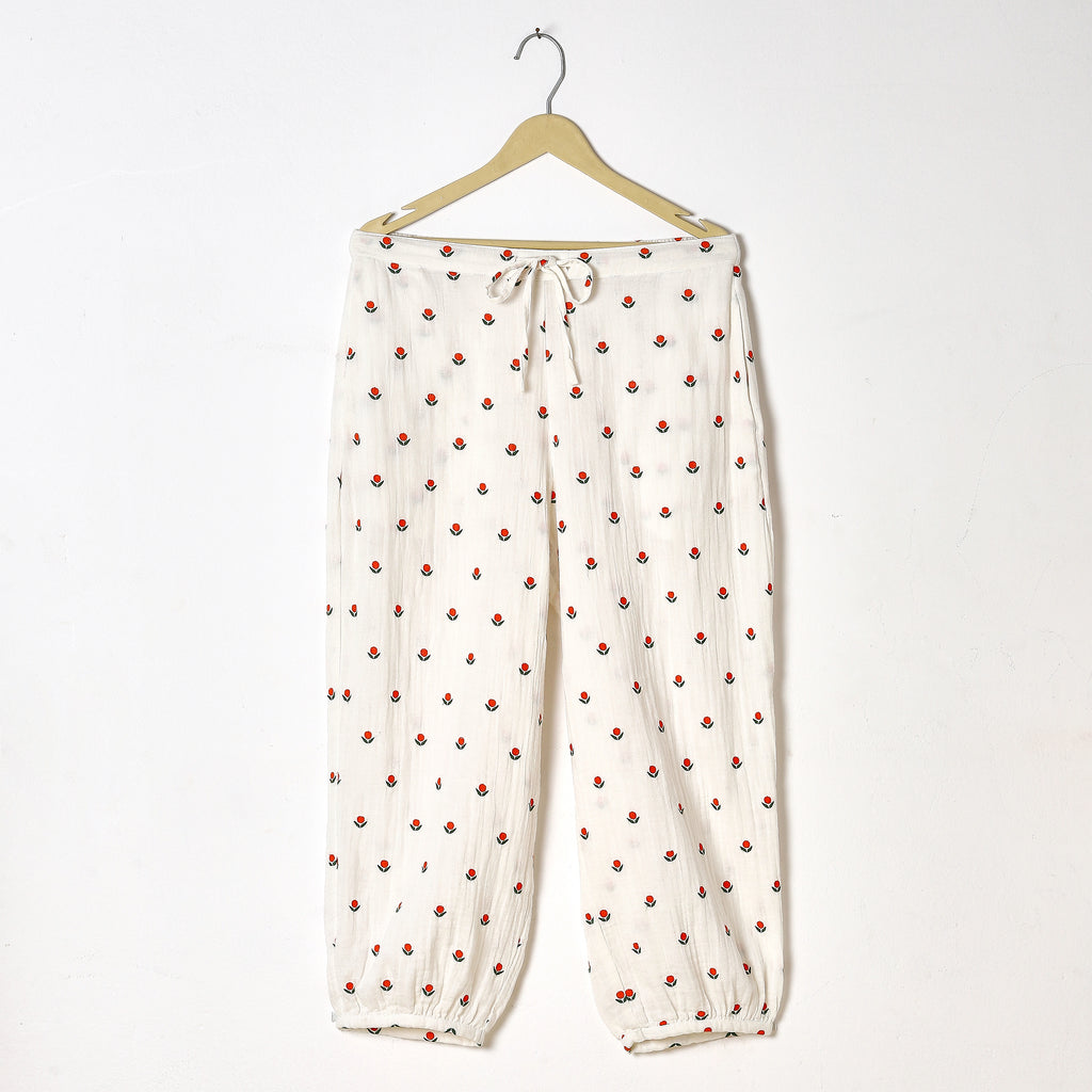 White pants with red floral pattern on a hanger against a white background