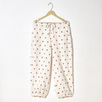 White pants with red floral pattern on a hanger against a white background