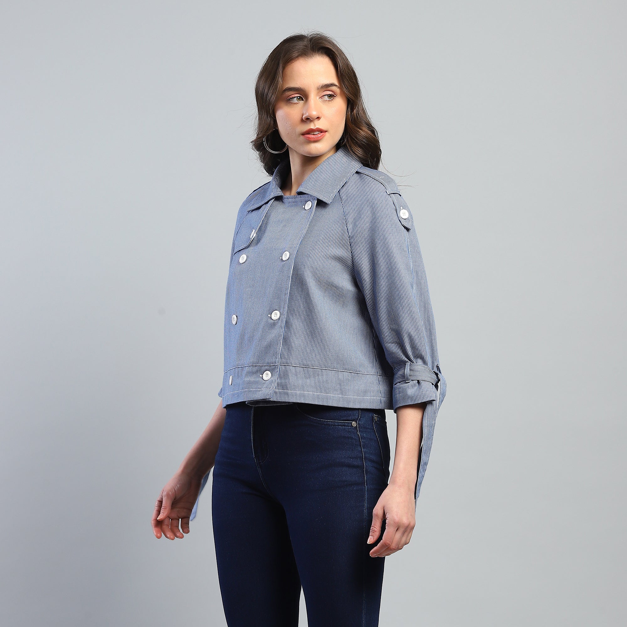 Woman wearing a light blue denim jacket on a gray background