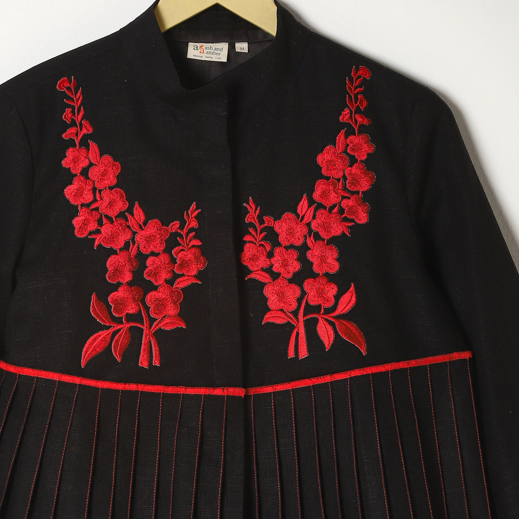 Black dress with red floral embroidery on a white background