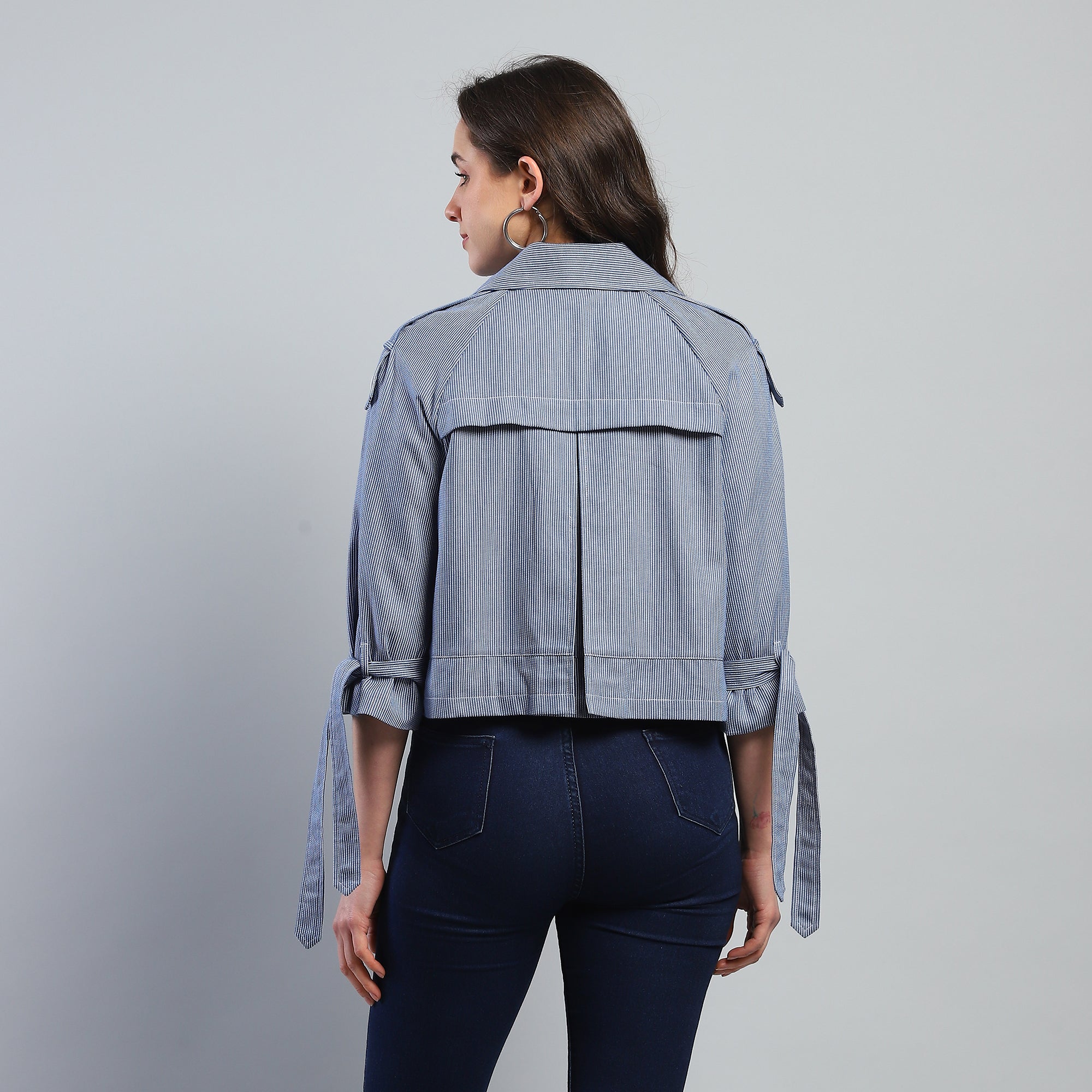 Woman wearing a light blue denim jacket on a gray background